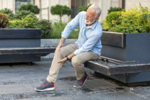 Senior Businessman with Knee Problems in the City Streets