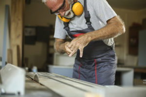 Senior man working as a carpenter in his workshop, injured with a circular saw. About 65 years old, Caucasian male.