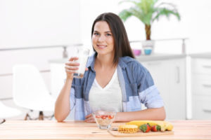 woman with milk and healthy breakfast in kitchen