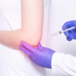 Doctor injects Corticosteroid to a young girl in a sore elbow joint